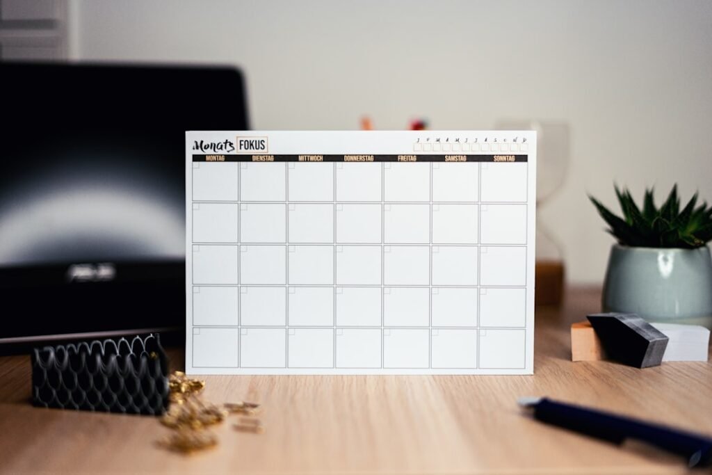 Clean white monthly calendar on a minimalist desk setup, representing organized daily learning schedules