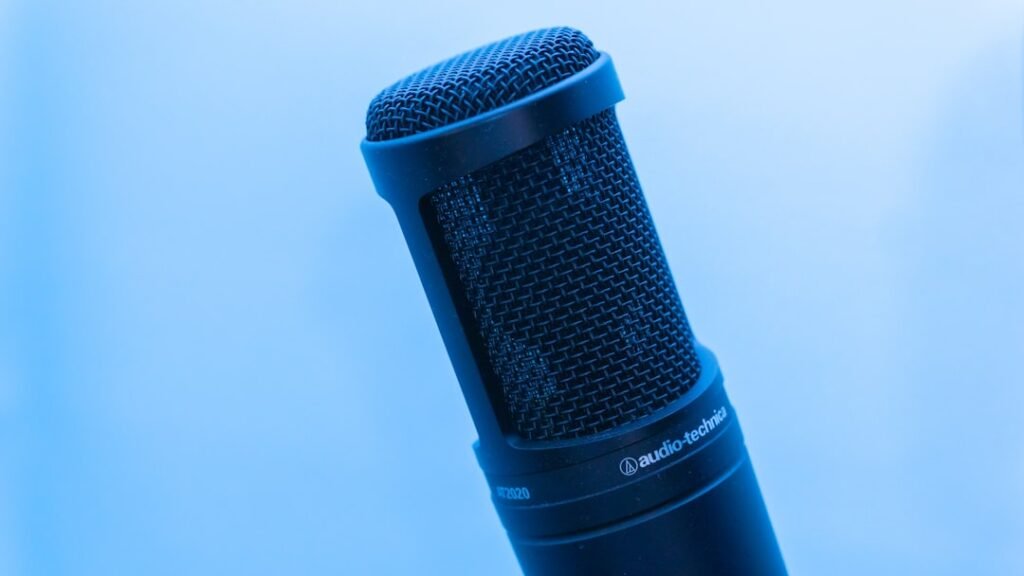Professional microphone on blue background representing speaking practice and audio output for language learning