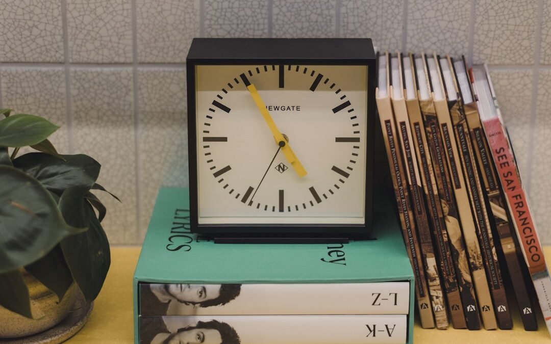 Minimalist desk clock sitting on a stack of books, representing focused and timed language learning sessions. Photo by Gemma Evans on Unsplash